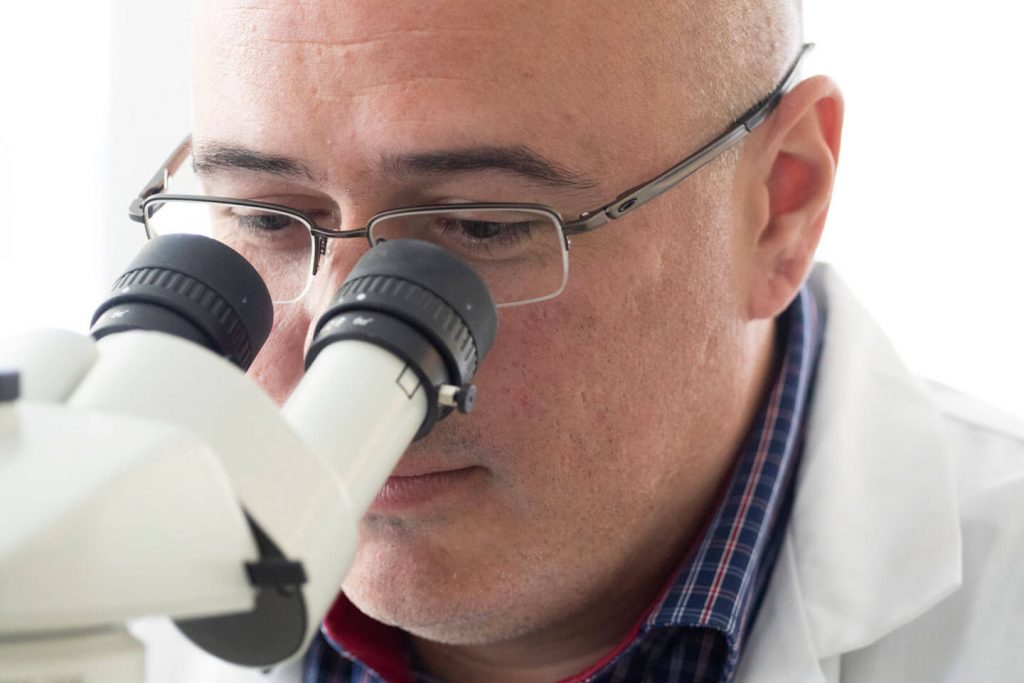 Dr. Daniel Coutu sits at a microscope