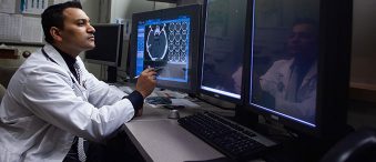 Dr. Nair looks at MRIs on computer screens