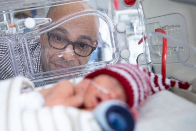 Dr. Bernard Thébaud looks at a premature baby in an isolette.