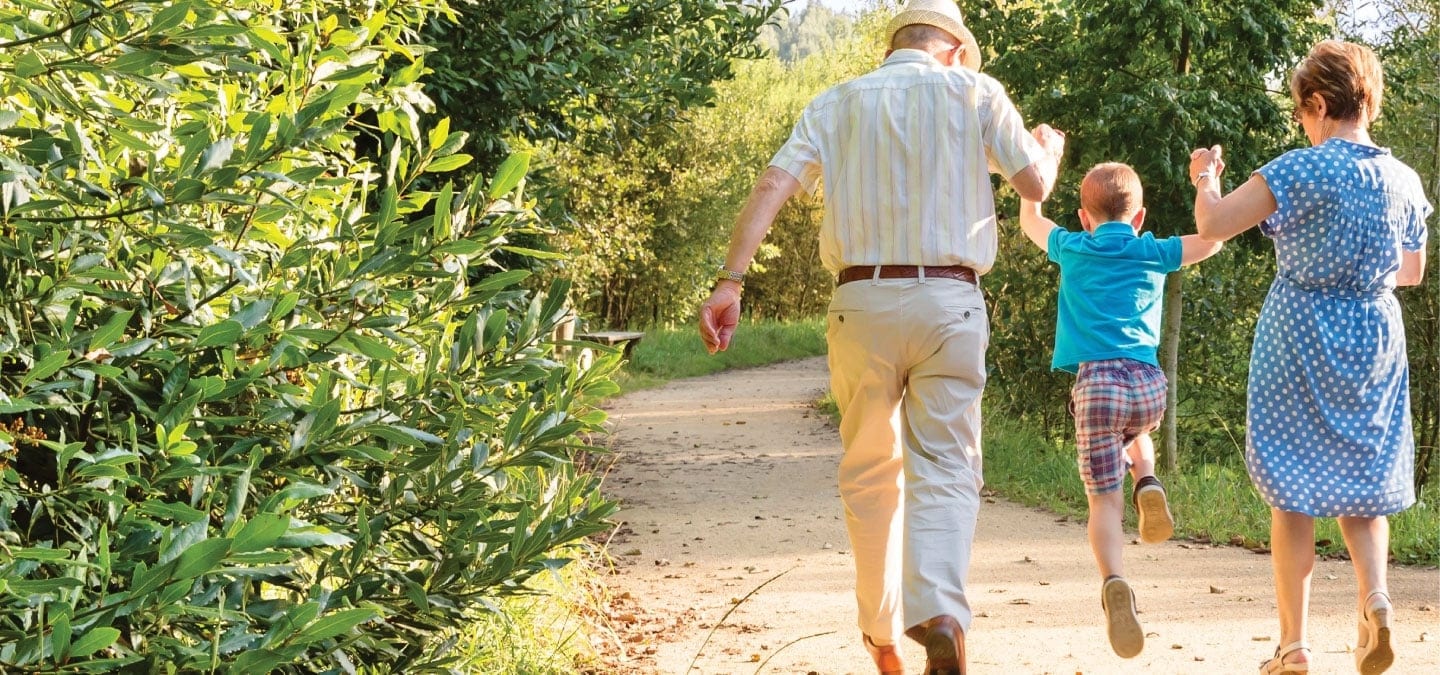 older people walking with small child in park
